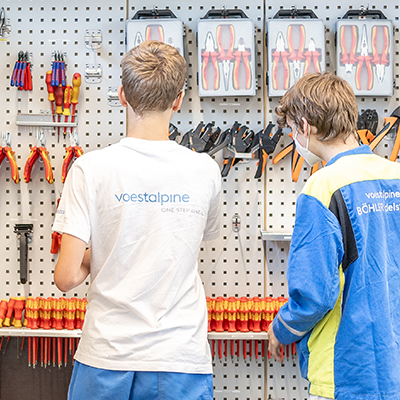 Lehrlinge vor Werkzeugwand